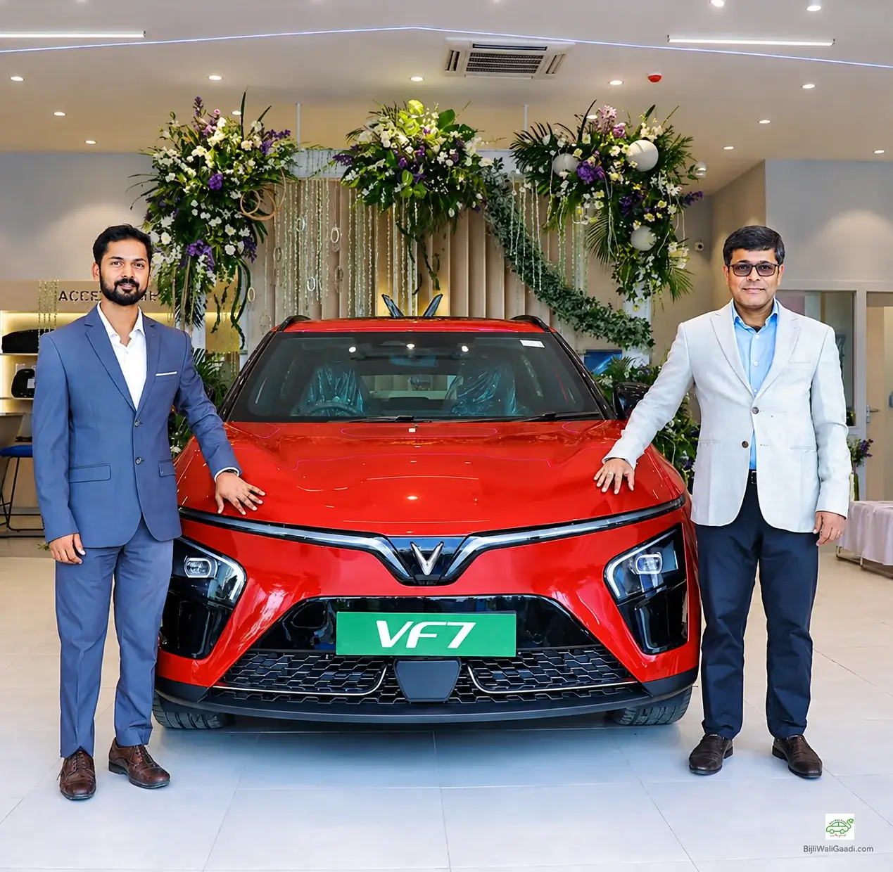 VinFast executives pose beside the red VinFast VF7 electric SUV during the inauguration of VinFast India's 60th dealership and first showroom in Bihar, Patna, with a small BijliWaliGaadi.com watermark in the bottom-right corner.