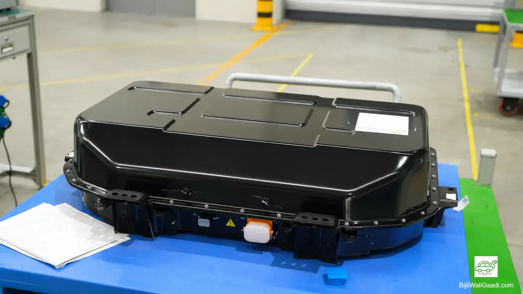 Top view of an open MG EV battery pack housing on an assembly workstation inside a modern manufacturing plant.